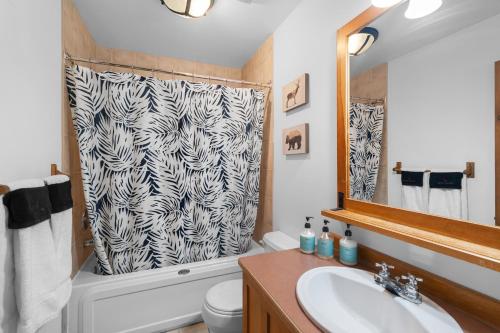 baño con lavabo y cortina de ducha en Les Falaises Tremblant - Ski Inout Condo W2bdrs en Mont-Tremblant