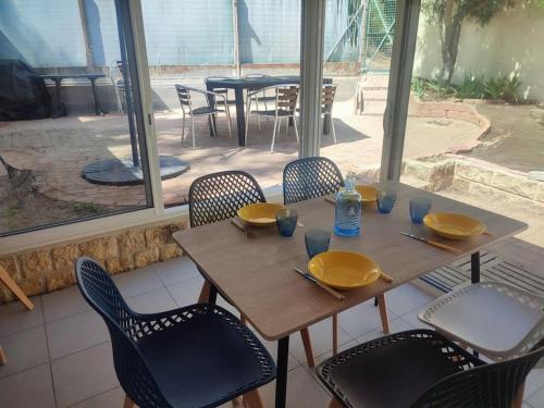- une table et des chaises en bois avec des assiettes et des bouteilles d'eau dans l'établissement L'olivier, à La Barre-de-Monts