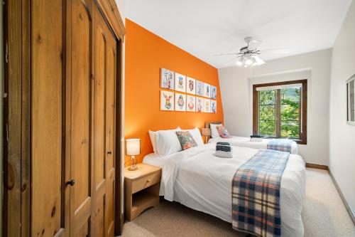 1 dormitorio con 2 camas y pared de color naranja en Les Manoirs 3bdrs Near Village, en Mont-Tremblant