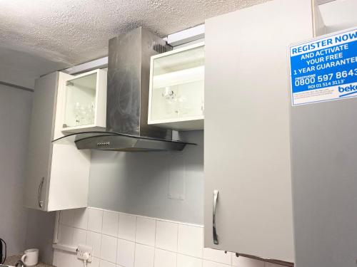 a kitchen with white cabinets and a stove top oven at London Studio in Chingford