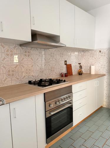 a kitchen with white cabinets and a stove top oven at Nina's Stay Hostel in Charneca