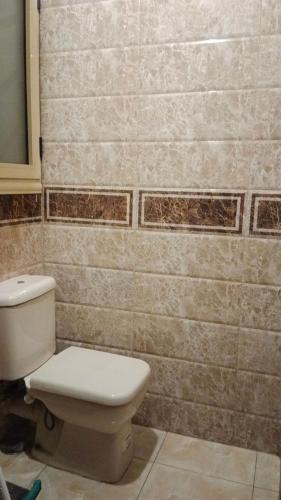 a bathroom with a toilet and a tiled wall at Pyramids Guest1 in Cairo