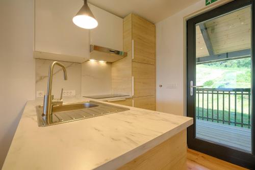 a kitchen with a sink and a large window at Apartments Pri Fencu in Jesenice