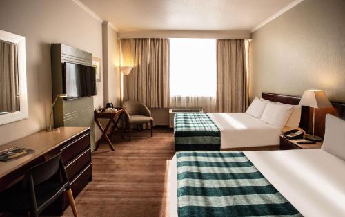 a hotel room with two beds and a television at Garden Court Kimberley in Kimberley