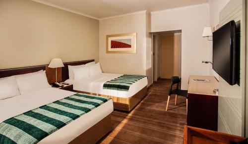 a hotel room with two beds and a flat screen tv at Garden Court Kimberley in Kimberley