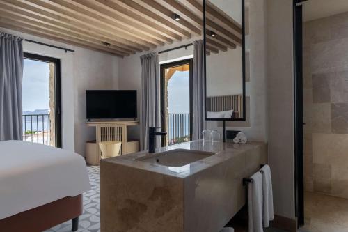 a bedroom with a bed and a bathroom with a sink at Radisson Blu Hotel, Kas in Kas