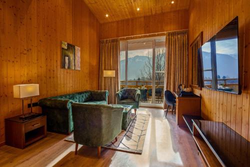 a living room with a green couch and a large window at Palchan Hotel & Spa - A member of Radisson Individuals Retreats in Manāli