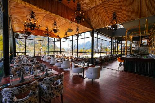 uma sala de jantar com mesas, cadeiras e janelas em Palchan Hotel & Spa - A member of Radisson Individuals Retreats em Manali