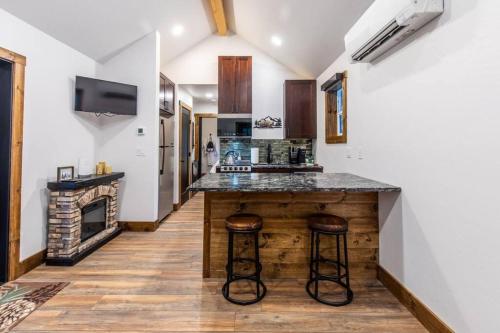 a kitchen with a counter with stools and a fireplace at Tall Pines a cozy 1 bedroom Tiny Cabin in Leavenworth