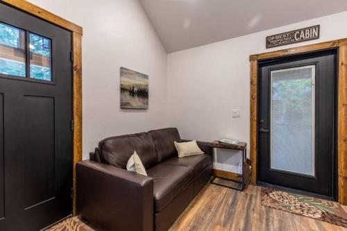 a living room with a brown leather couch and a door at Tall Pines a cozy 1 bedroom Tiny Cabin in Leavenworth