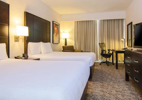 a hotel room with two beds and a desk at Hilton Garden Inn Tuxtla Gutierrez in Tuxtla Gutiérrez