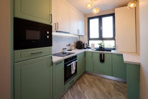 a kitchen with green cabinets and a black microwave at Luxurious Apartment, Best View in Timişoara