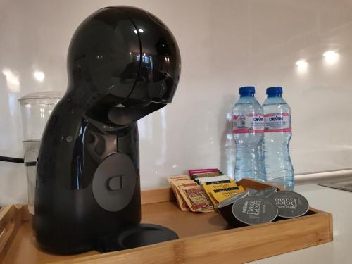 a black blender sitting on a shelf next to water bottles at Apartment Lora in Burgas
