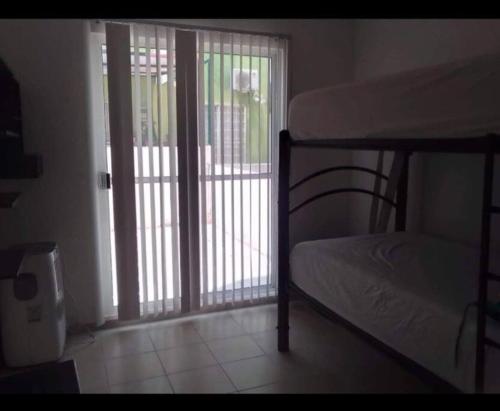 a bedroom with a bunk bed and a sliding glass door at Departamento ACAPULCO PROMOCIÓN in Aguacatillo