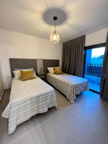 a bedroom with two beds and a large window at COMPLEJO VICTORIO in San Luis