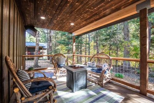 a screened in porch with wicker chairs and a stove at Lake House tiny cabin near Lake Wenatchee in Leavenworth