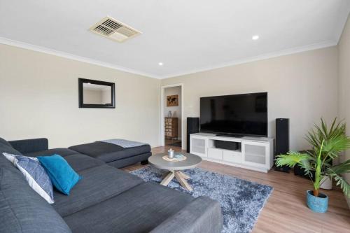 a living room with a couch and a tv at Spacious 3BR house with a cosy log fire & luxury spa bath in Kalgoorlie