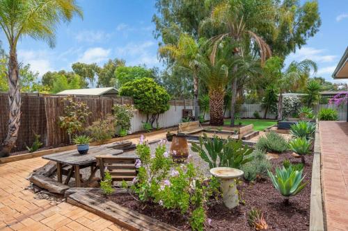 a garden with a wooden table and benches at Jarvis Place Spacious 3BR house with a cosy log fire & luxury spa bath in Kalgoorlie