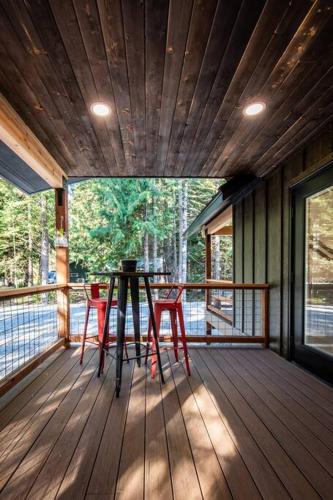 Ski Chalet A cozy little cabin in the woods near Lake Wenatchee في ليفنوورث: شرفة مع طاولة وكراسي على السطح