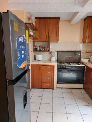 a kitchen with a stainless steel refrigerator and wooden cabinets at Acogedor departamento in Loja