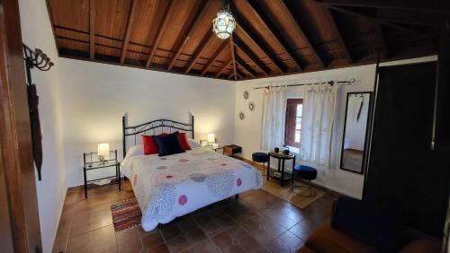 Un dormitorio con una cama con almohadas rojas. en CASA TIO MANUEL, en La Tierra del Trigo