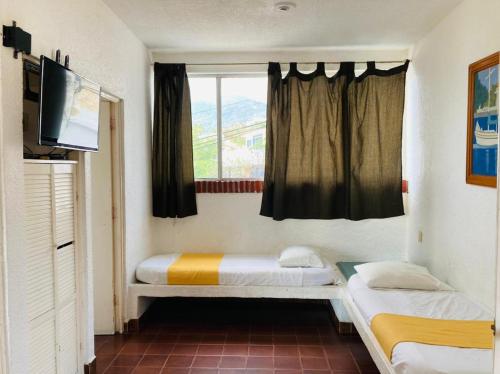 a small room with two beds and a window at Suites Acapulco Yamba in Acapulco