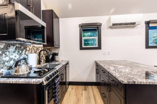 a kitchen with black cabinets and a stove top oven at Bear Den a Cozy 1 Bedroom tiny Cabin near Lake Wenatchee in Leavenworth