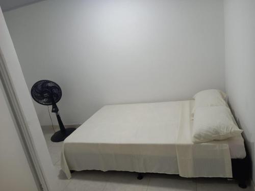 Schlafzimmer mit einem weißen Bett und einem Ventilator in der Unterkunft Hotel Romadar in Puerto López