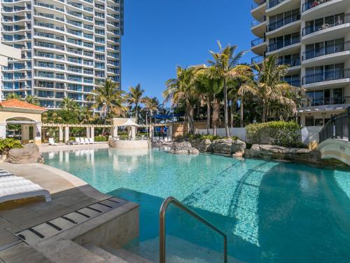 a swimming pool with palm trees and buildings at Chevron Renaissance - Private Apartments - Hosted by Coastal Letting Co. in Gold Coast