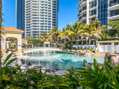 a swimming pool with palm trees and buildings at Chevron Renaissance - Private Apartments - Hosted by Coastal Letting Co. in Gold Coast