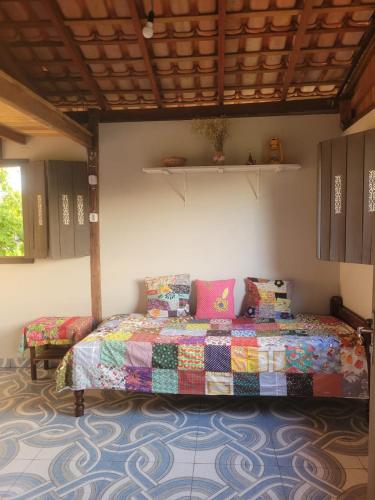 a bedroom with a bed with a colorful comforter at Hospedagem Casinha do Solar in Soure