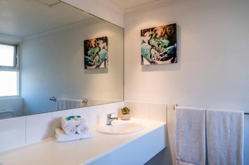 a white bathroom with a sink and a mirror at Glenelg Central Studio Aqua in Glenelg