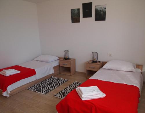 two beds in a room with red and white sheets at Apartment Nadalina in Kraljevica
