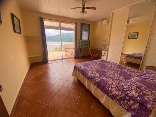 Schlafzimmer mit einem Bett und einer Tür zu einem Balkon in der Unterkunft Te Mana Lodge in Taravao