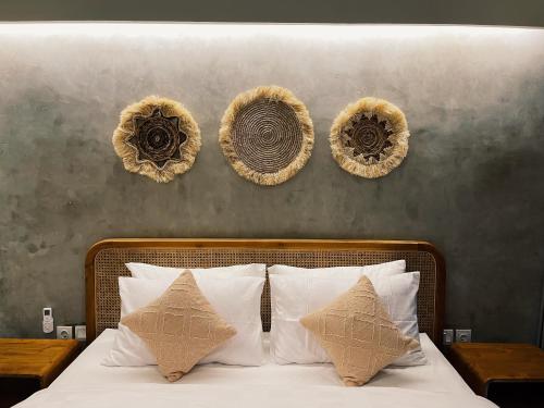 a bed with white pillows and three baskets on the wall at Griya tropical in Ubud