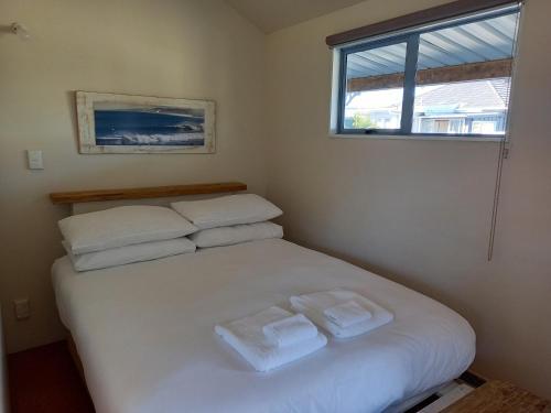 1 dormitorio con 1 cama con 2 toallas en Raglan West Accommodation Units, en Raglan