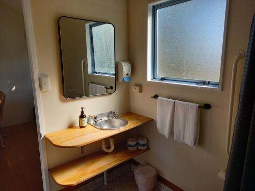 W łazience znajduje się umywalka i lustro. w obiekcie Raglan West Accommodation Units w mieście Raglan