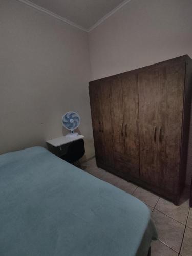 um quarto com uma cama e um armário de madeira em Quarto Privado em Franca