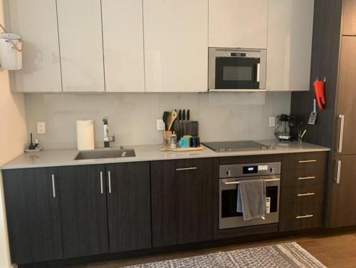 a kitchen with white cabinets and a sink and a stove at Beautiful 1Bd Entertainment disrtrict. in Toronto