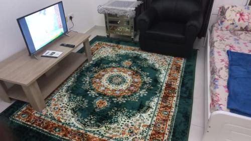 a living room with a television and a table and a rug at Budget Place in Dubai