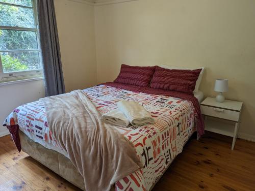 a bed with red pillows and a blanket on it at A Classic Deakin Delight in Yarralumla