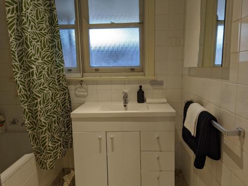 a bathroom with a sink and a shower curtain at A Classic Deakin Delight in Yarralumla