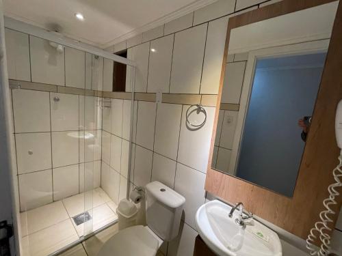 W łazience znajduje się toaleta, umywalka i lustro. w obiekcie Hospedar Flats & Residence w mieście Santa Cruz do Sul