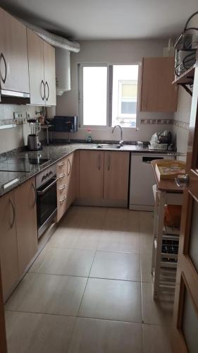 a kitchen with wooden cabinets and a large window at holiday hogar altea in Altea