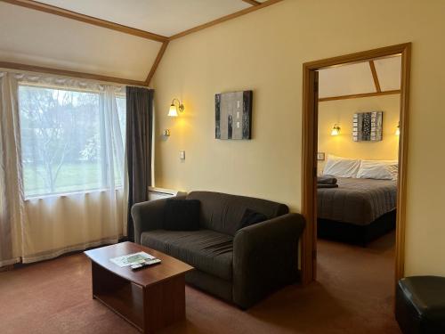 a living room with a couch and a bed and a mirror at Masterton Motor Lodge in Masterton