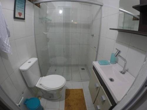 a white bathroom with a toilet and a sink at Chalé Tiririca pé na areia in Itacaré