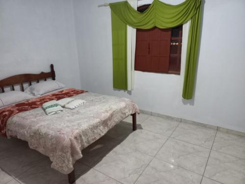 Schlafzimmer mit einem Bett mit grünen Vorhängen und einem Fenster in der Unterkunft Mini lar próximo ao parque in Caparaó Velho