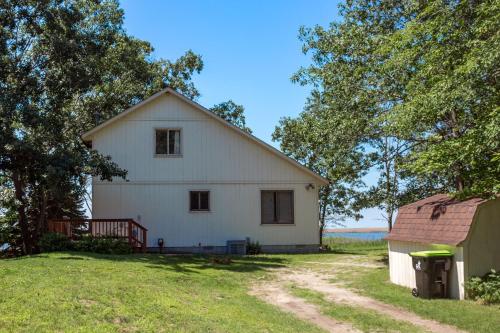 Ein weißes Haus auf einem Feld mit einem Baum in der Unterkunft Lakeview & Wildlife in Au Gres