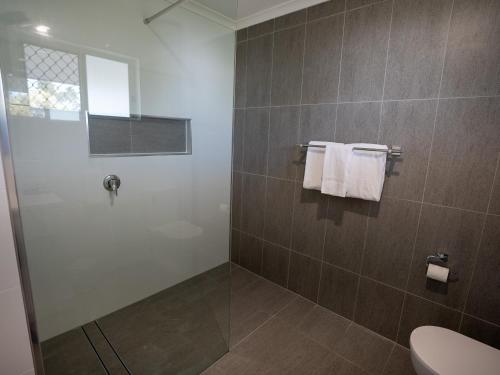 a bathroom with a shower and a toilet and towels at Best Western Ambassador Motor Lodge in Hervey Bay