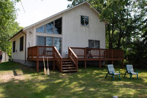 a house with a large deck and two chairs in the yard at Lakeview & Wildlife in Au Gres
